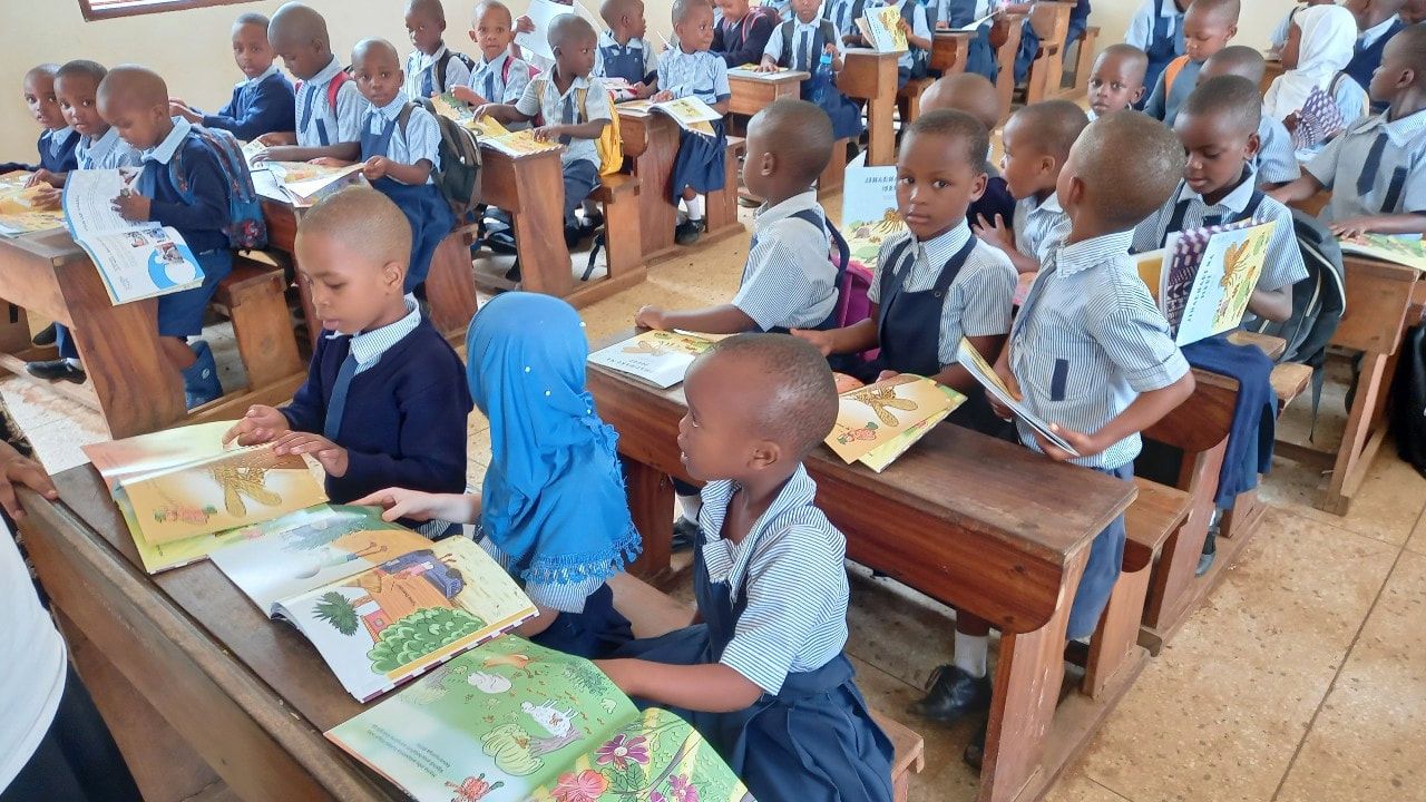 A classroom of Tanzanian children holding their new picture books