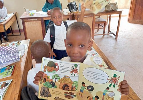 A child at Tumbi Primary School holding an open picture book
