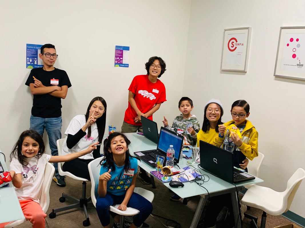 Teen volunteers and children smiling around laptops at the first Voice of Dream camp