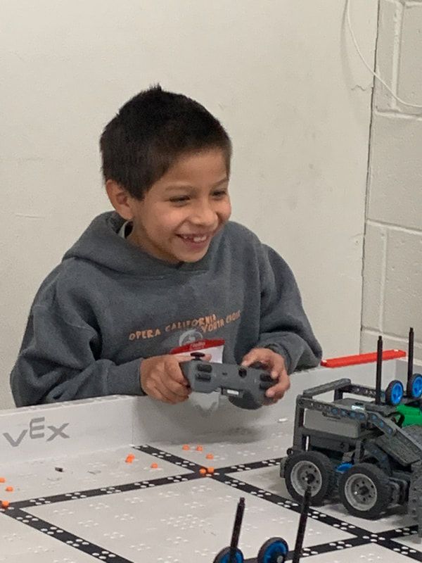 A boy laughing as he holds a robot controller