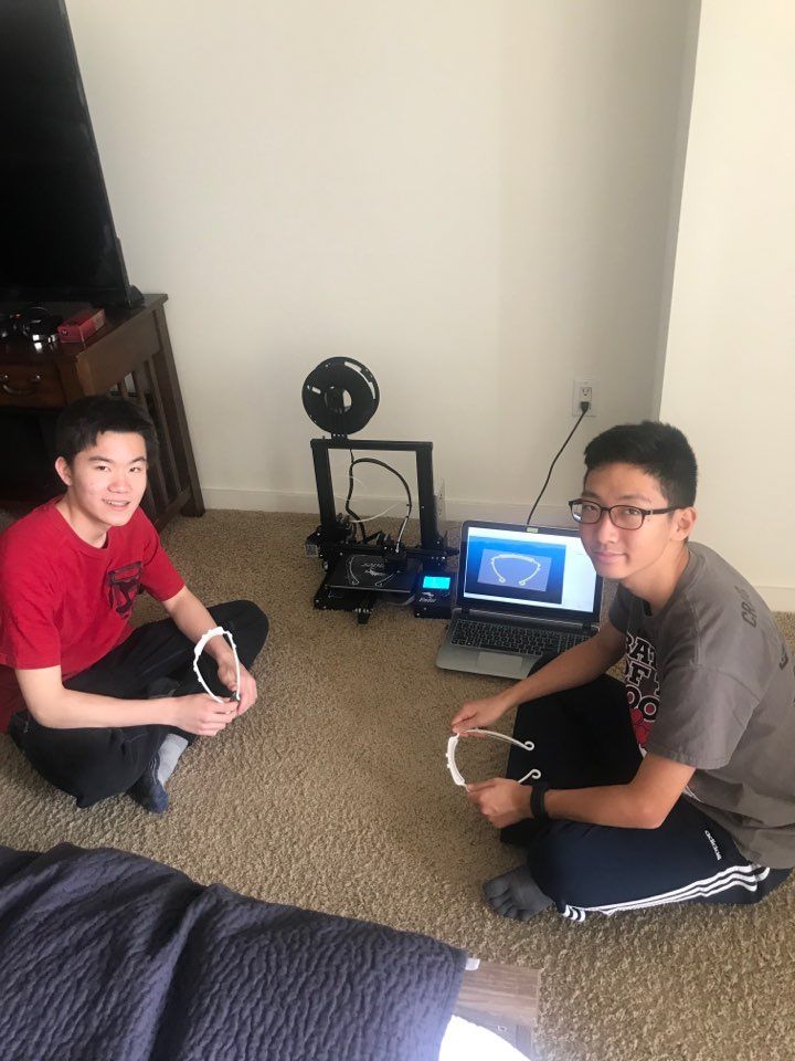 Two members running the 3D printer at home
